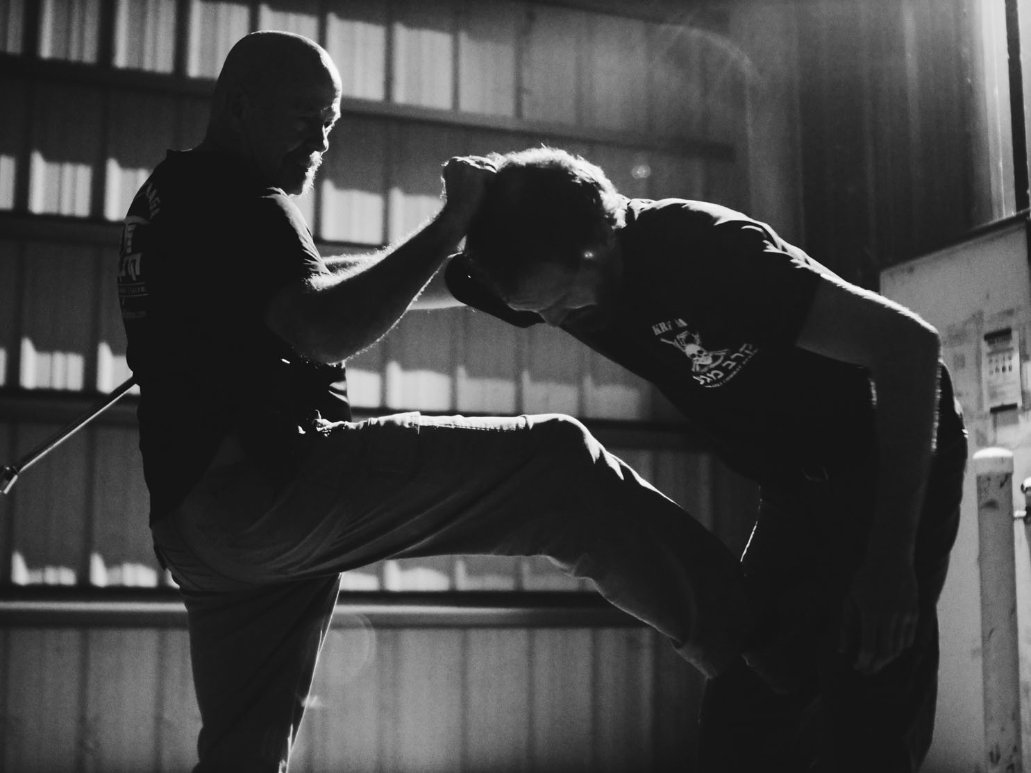 Two men practicing martial arts in warehouse.