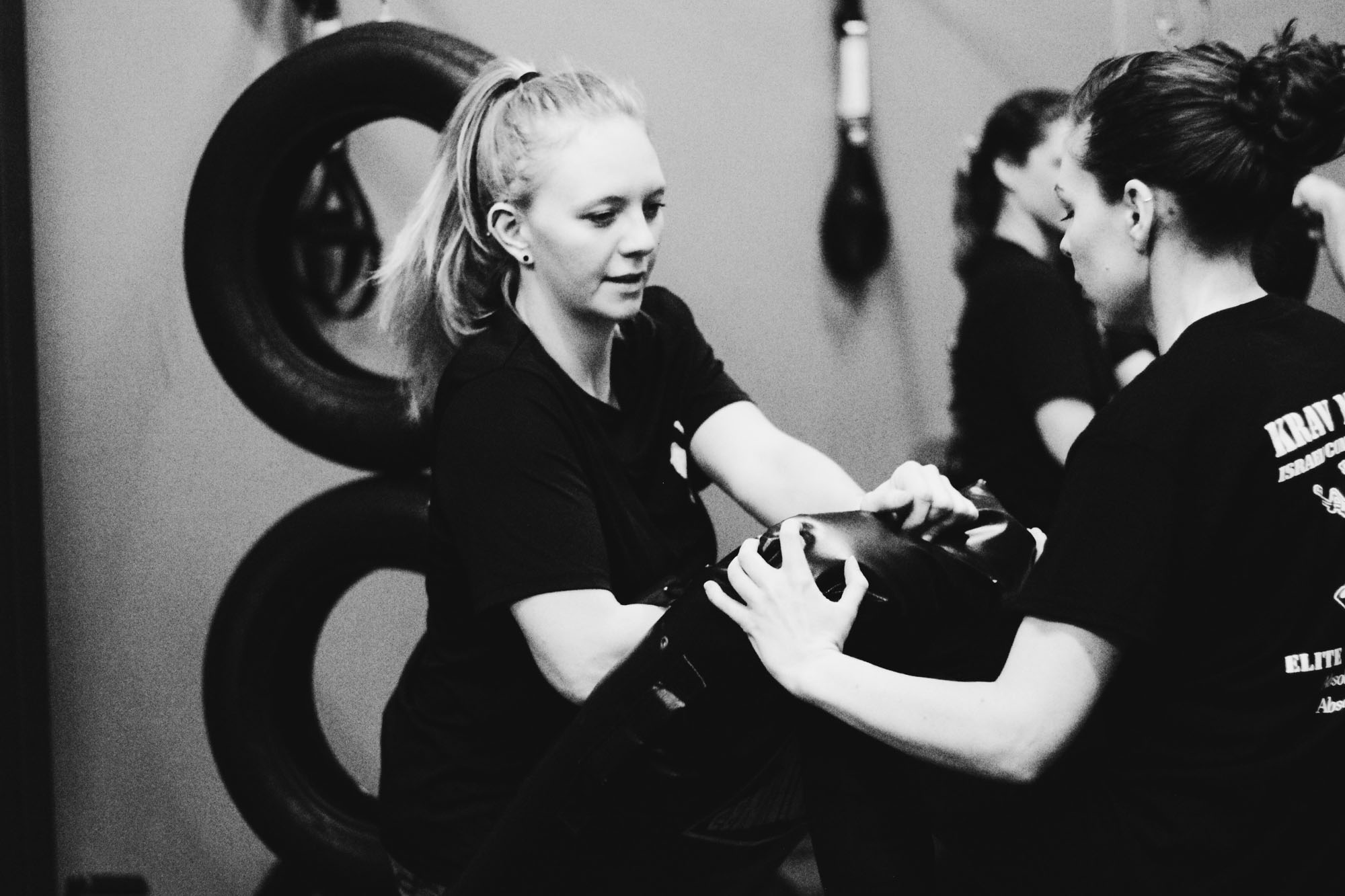 Women practicing self-defense in a gym.